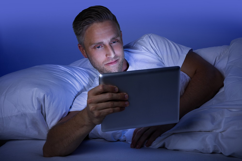 Blue light skincare HEV, man browsing tablet at night