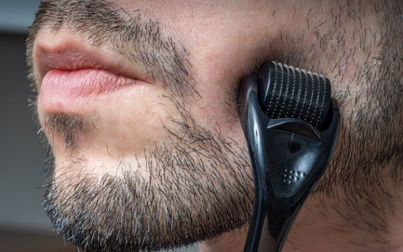 Man microneedling skin and scalp for hair growth